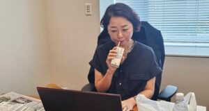 ノートPCに向かい水分補給をおこないつつ執務にあたる安藤じゅん子